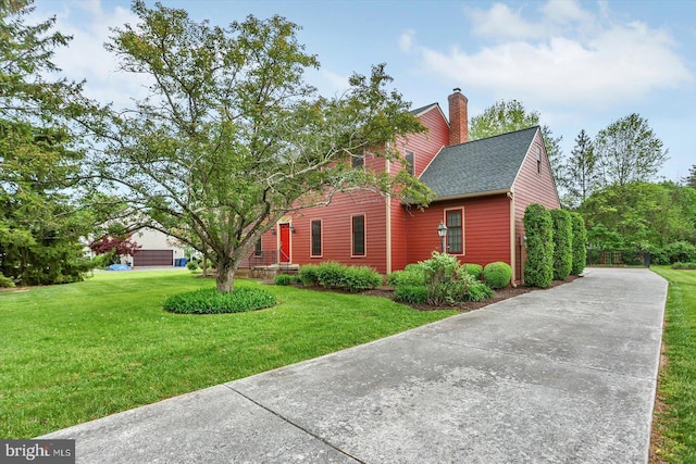view of side of property with a shingled roof, a chimney, and a yard