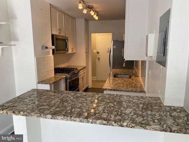 kitchen with stone countertops, a sink, appliances with stainless steel finishes, and backsplash