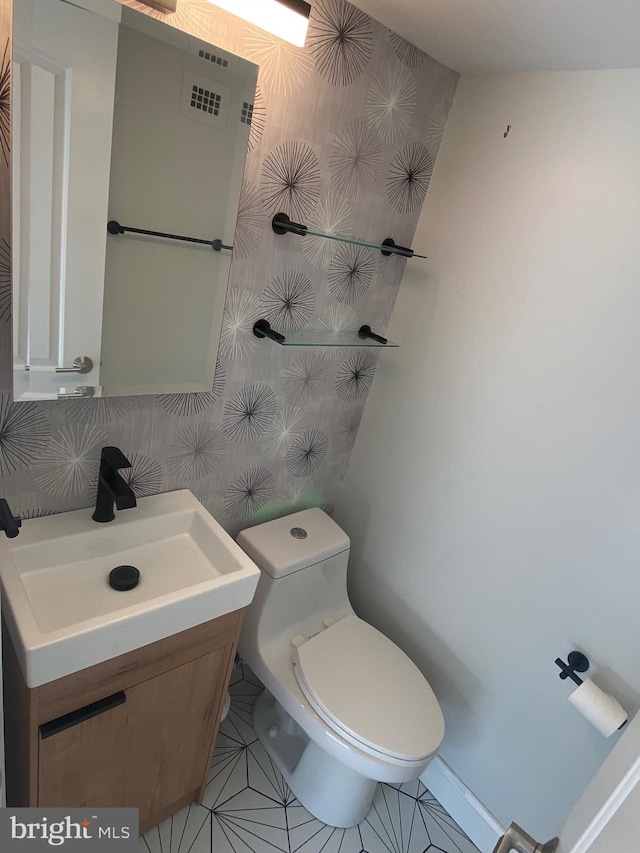 bathroom with baseboards, vanity, tile patterned floors, toilet, and wallpapered walls