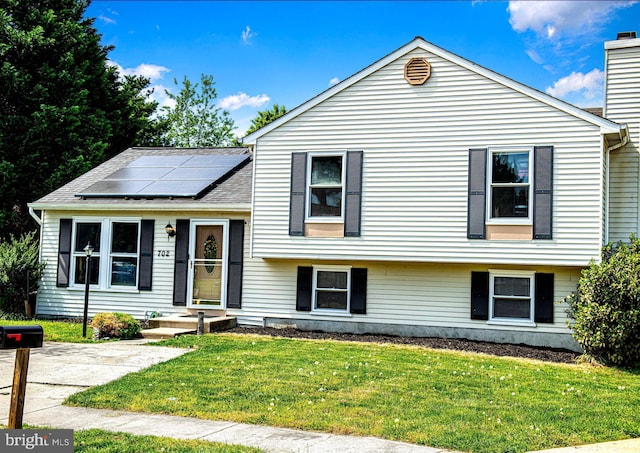 702 Rainbow Ct, Edgewood, MD 21040 - split level home with roof mounted solar panels, a chimney, a shingled roof, and a front lawn