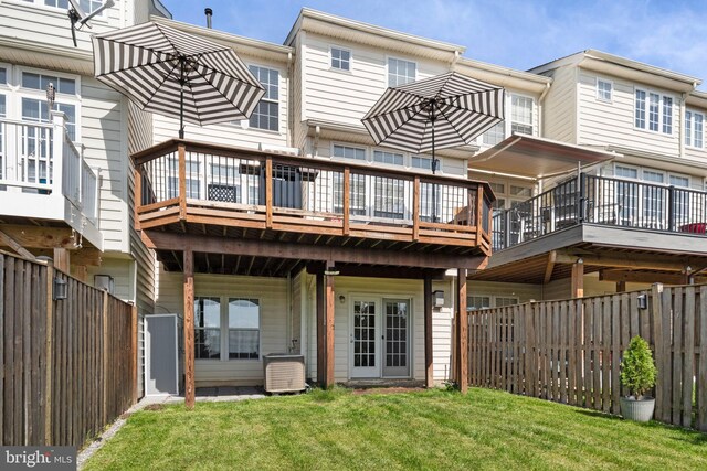 rear view of property with a lawn, a deck, central AC unit, and a fenced backyard