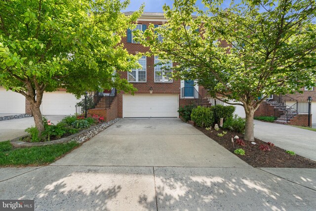 townhome / multi-family property featuring brick siding, a garage, driveway, and stairway