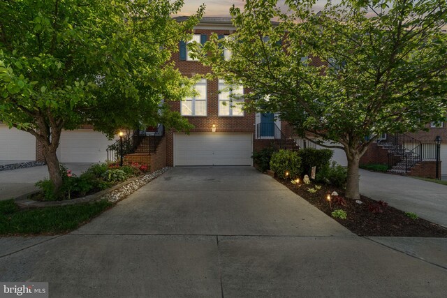 view of front of home with stairs, an attached garage, concrete driveway, and brick siding