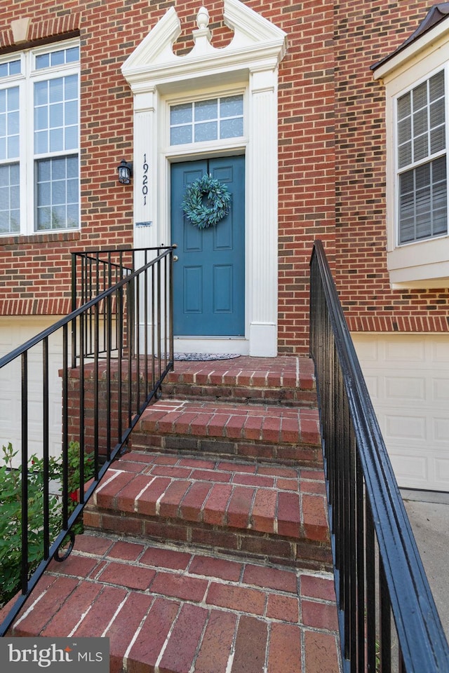 entrance to property with a garage and brick siding