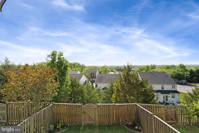 exterior space featuring a gate, a fenced backyard, and a residential view