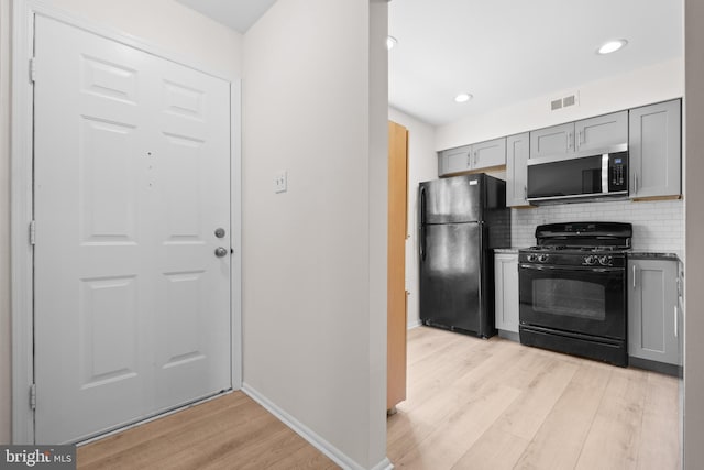 kitchen with visible vents, decorative backsplash, light wood-style floors, gray cabinets, and black appliances