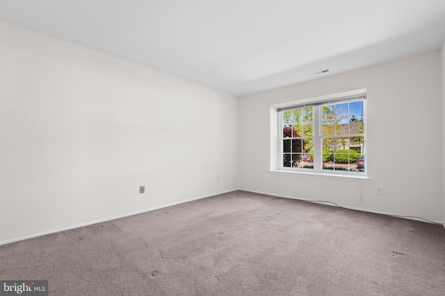 carpeted empty room featuring visible vents and baseboards