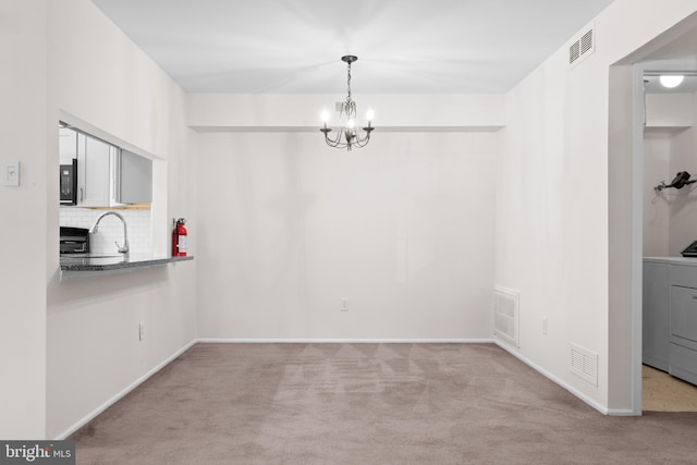 unfurnished dining area featuring visible vents, carpet flooring, and a chandelier