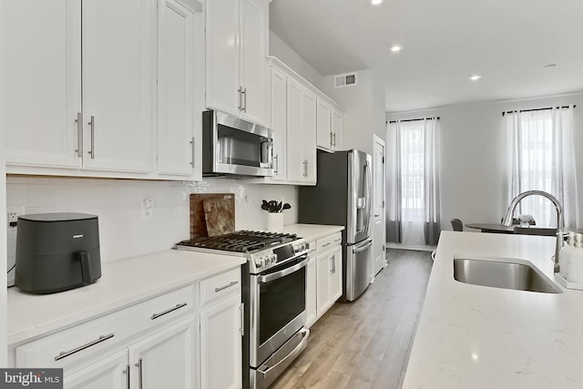 1701 Beech Leaf St, Dumfries, VA 22026 - kitchen featuring appliances with stainless steel finishes, a sink, white cabinets, recessed lighting, and light wood-style flooring
