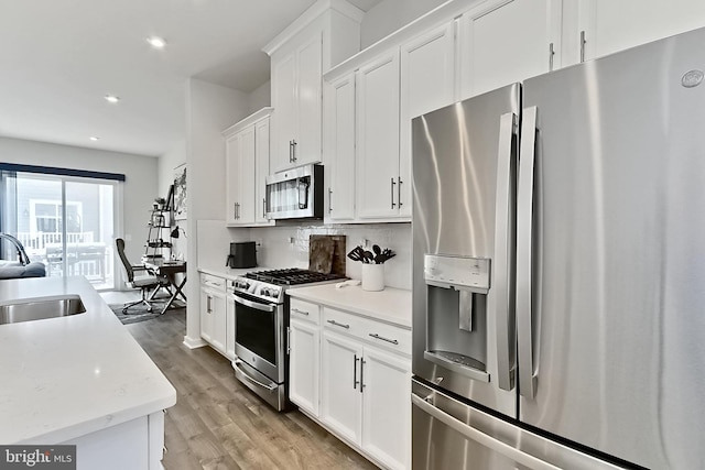 1701 Beech Leaf St, Dumfries, VA 22026 - kitchen featuring appliances with stainless steel finishes, a sink, white cabinets, light wood-style floors, and recessed lighting