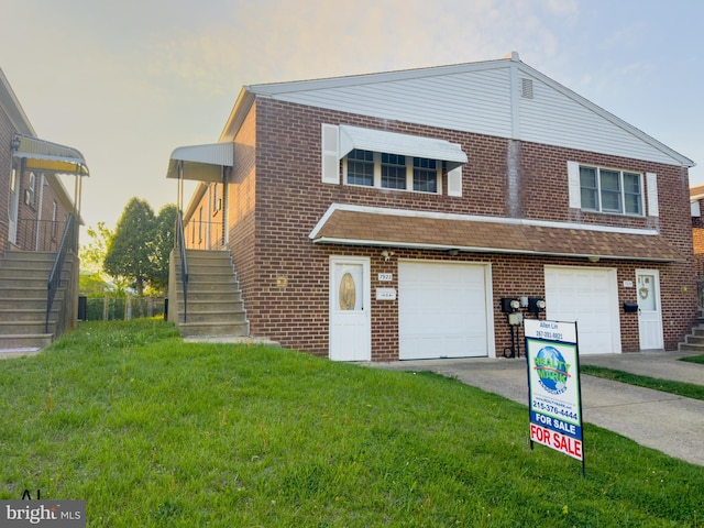 view of front of property with a front lawn, concrete driveway, stairway, and brick siding
