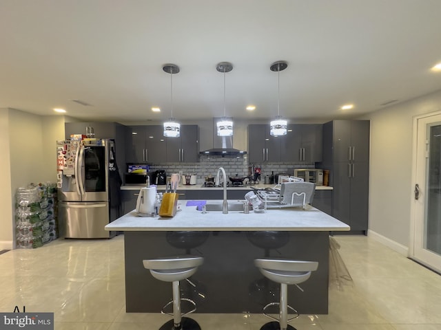 kitchen featuring wall chimney range hood, stainless steel fridge with ice dispenser, light countertops, decorative backsplash, and a kitchen bar