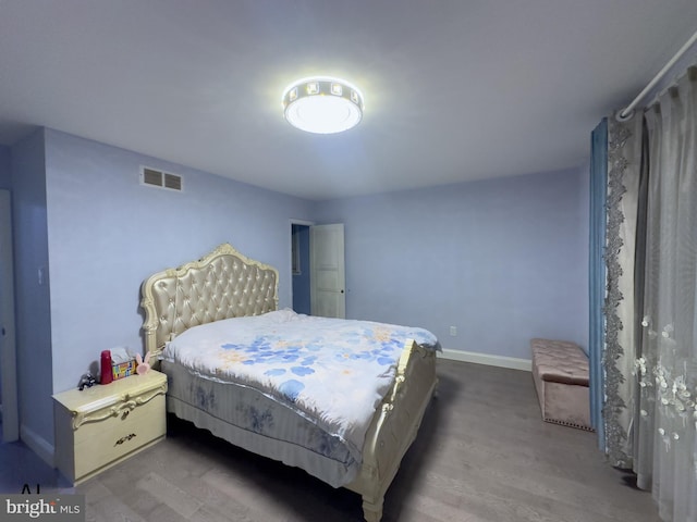 bedroom featuring visible vents, baseboards, and wood finished floors
