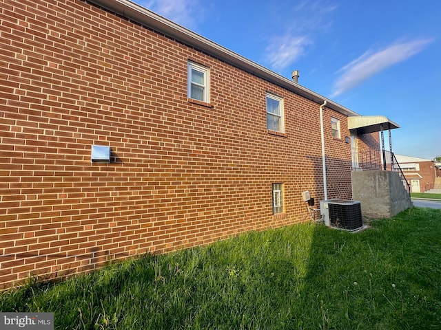 view of side of home featuring a lawn and central AC