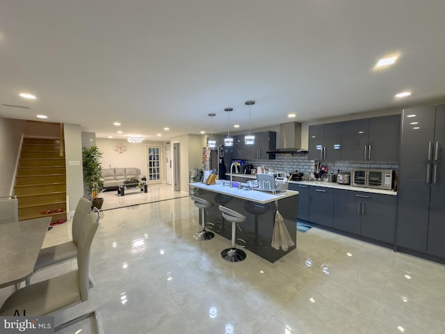 kitchen featuring modern cabinets, light countertops, a breakfast bar, recessed lighting, and wall chimney exhaust hood