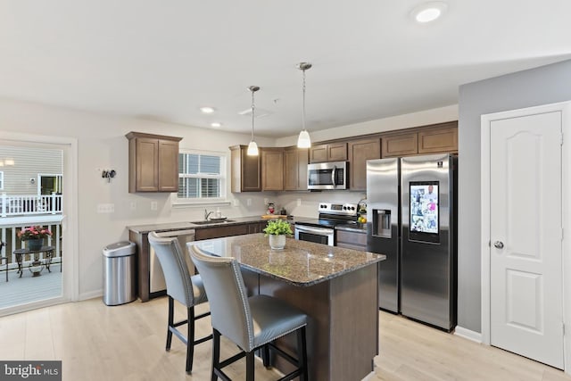 209 Sheridan St, Taneytown, MD 21787 - kitchen featuring appliances with stainless steel finishes, a sink, light wood-type flooring, a kitchen breakfast bar, and dark stone counters