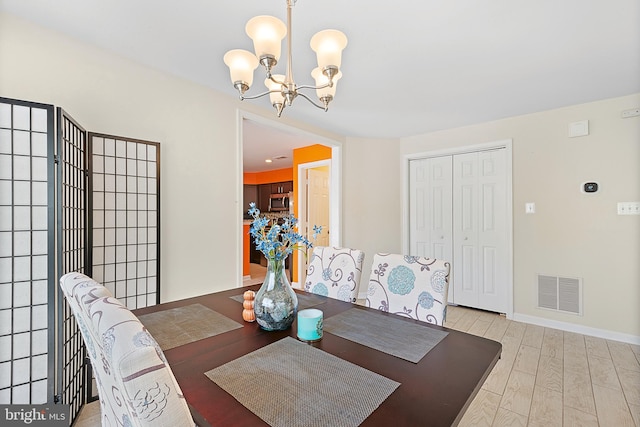 dining area with a chandelier, light wood-style floors, visible vents, and baseboards
