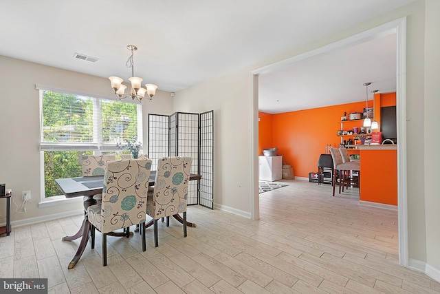 dining area featuring baseboards, an inviting chandelier, visible vents, and light wood-style flooring