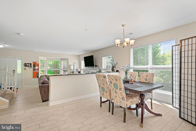 dining space with light wood finished floors, baseboards, and a chandelier