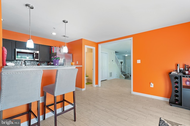 kitchen featuring hanging light fixtures, light wood-style flooring, baseboards, light countertops, and appliances with stainless steel finishes