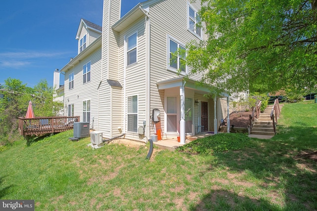 view of side of property featuring a yard, a chimney, a deck, and central AC