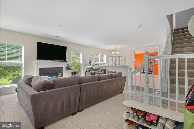 living area with stairway, an inviting chandelier, visible vents, light wood-style floors, and a fireplace