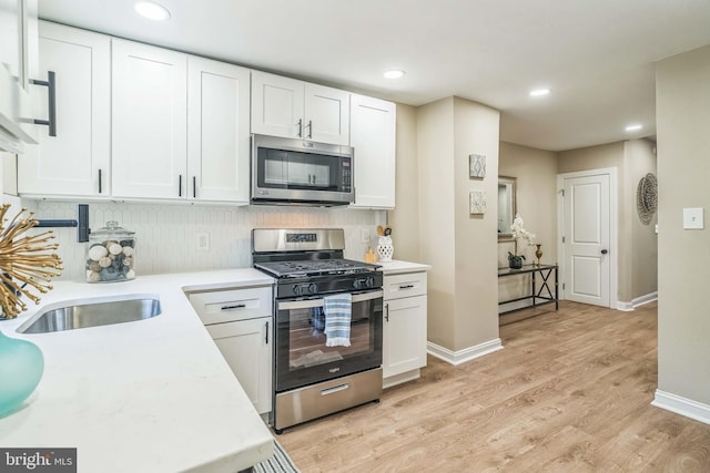 226 N 64th St, Philadelphia, PA 19139 - kitchen with tasteful backsplash, light countertops, light wood-style floors, stainless steel appliances, and white cabinetry