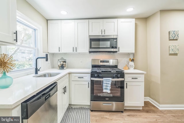 226 N 64th St, Philadelphia, PA 19139 - kitchen with appliances with stainless steel finishes, a sink, light wood-style flooring, white cabinetry, and a wealth of natural light