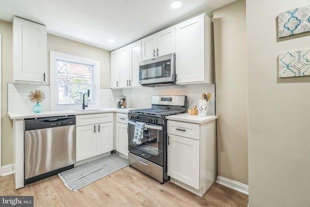226 N 64th St, Philadelphia, PA 19139 - kitchen featuring light wood-type flooring, a sink, white cabinetry, and stainless steel appliances