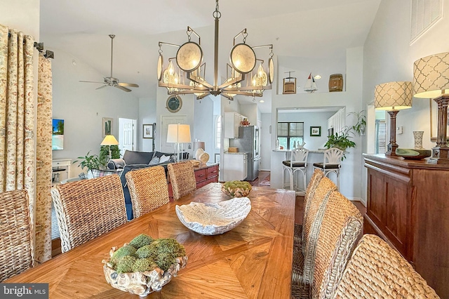 dining space with high vaulted ceiling, visible vents, and ceiling fan with notable chandelier