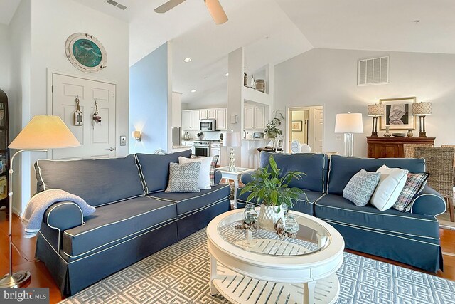 living room featuring a ceiling fan, high vaulted ceiling, visible vents, and wood finished floors