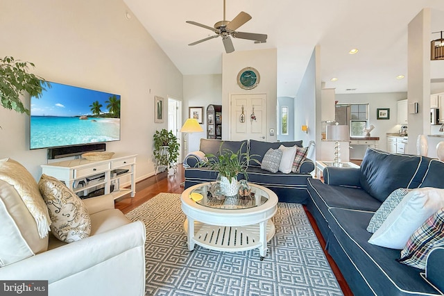 living room with a ceiling fan, baseboards, wood finished floors, and high vaulted ceiling