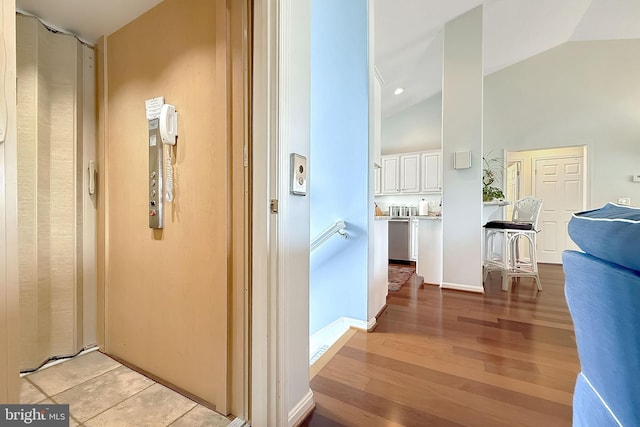 hallway with high vaulted ceiling and light wood finished floors