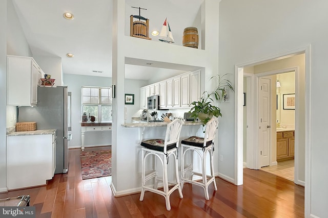 kitchen featuring stainless steel appliances, baseboards, white cabinetry, and wood finished floors
