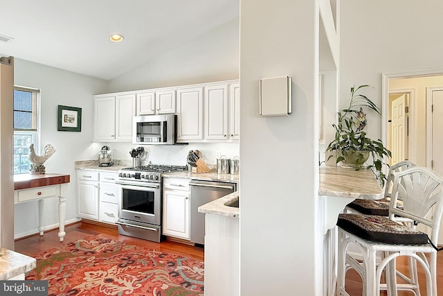 kitchen with dark wood finished floors, appliances with stainless steel finishes, white cabinets, and high vaulted ceiling