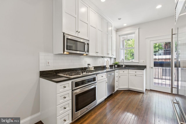 1847 Lamont St NW, Washington, DC 20010 - kitchen with stainless steel appliances, dark wood-style flooring, dark countertops, backsplash, and white cabinetry