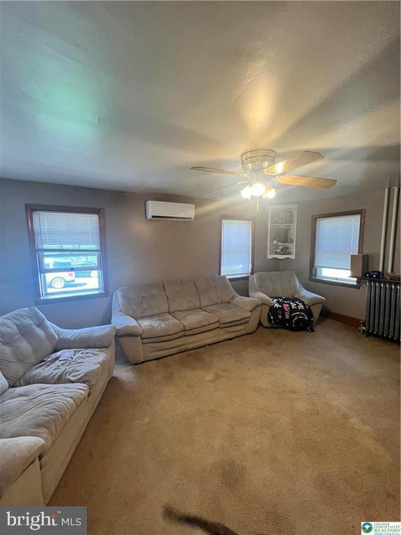carpeted living room with ceiling fan, radiator, a healthy amount of sunlight, and an AC wall unit