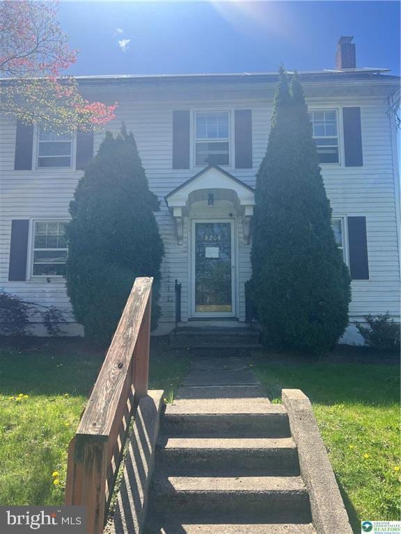 view of front of house featuring a chimney and a front lawn