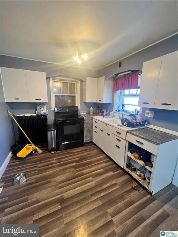 kitchen featuring a sink, dark wood finished floors, black range with electric cooktop, and white cabinets