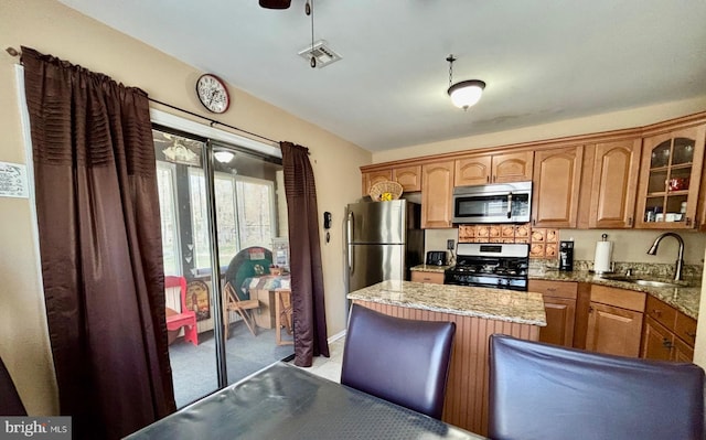 113 Lexington Dr, Tuckerton, NJ 08087 - kitchen featuring appliances with stainless steel finishes, a sink, glass insert cabinets, brown cabinetry, and a center island