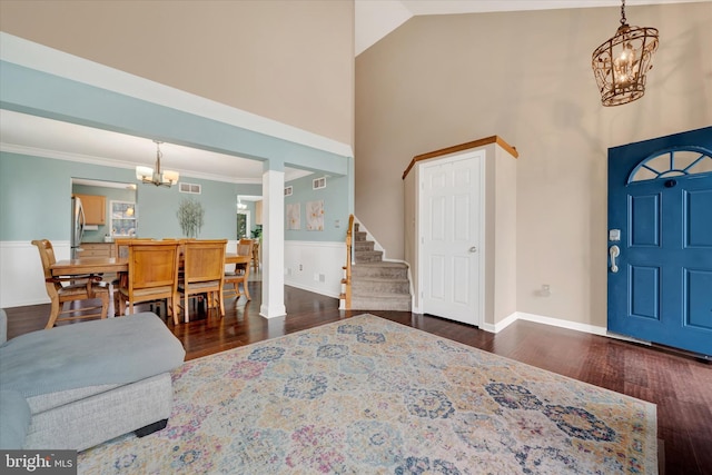 foyer entrance featuring stairway, a towering ceiling, a notable chandelier, and dark wood finished floors