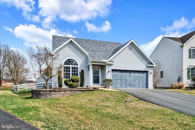 view of front of house with driveway, an attached garage, fence, and a front yard