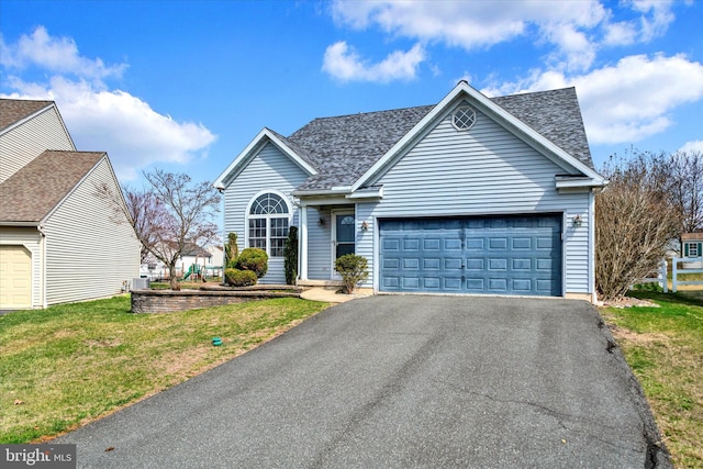view of front of house with a front lawn, roof with shingles, aphalt driveway, and a garage