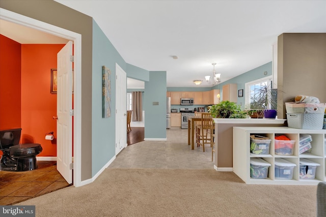 interior space featuring stainless steel appliances, light colored carpet, baseboards, light countertops, and a notable chandelier