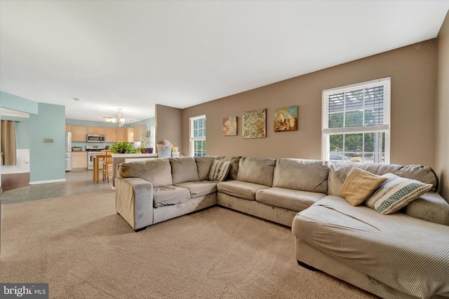 living area with light carpet, a notable chandelier, and baseboards