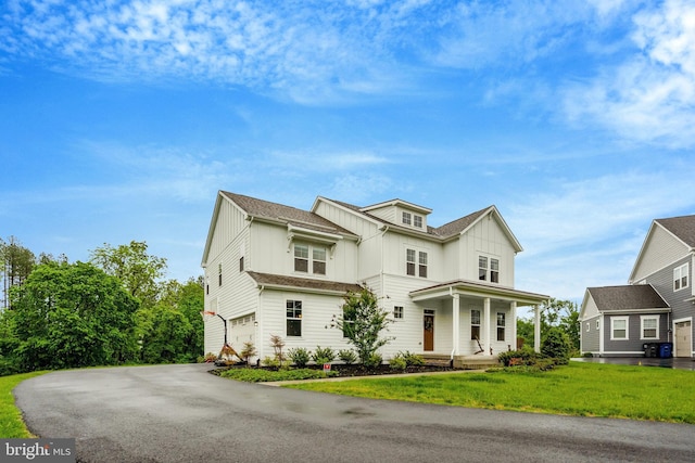 40928 Arcadian Pond Ct, Aldie, VA 20105 - view of front facade featuring board and batten siding, covered porch, asphalt driveway, a garage, and a front lawn