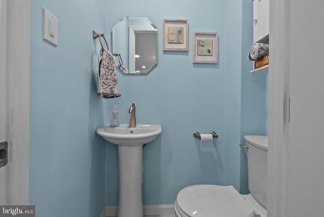 half bath with baseboards and toilet