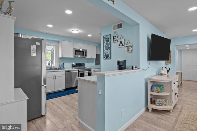 kitchen with a sink, appliances with stainless steel finishes, white cabinetry, and visible vents