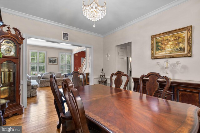 dining area featuring a notable chandelier, ornamental molding, light wood-style flooring, and visible vents