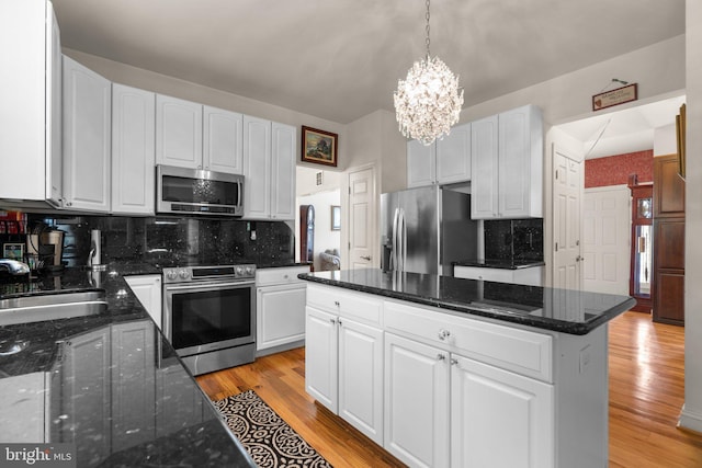 kitchen with stainless steel appliances, light wood finished floors, white cabinetry, and a chandelier